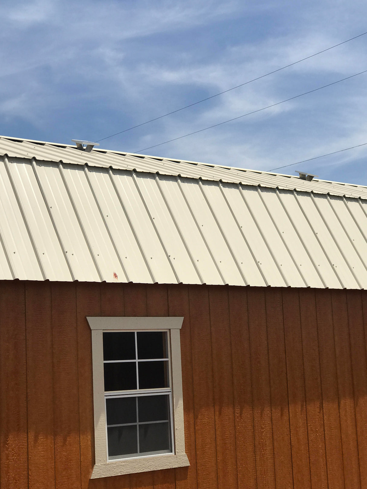 Two Solar Metal RidgeBlasters installed on a brown shed with a beige metal roof.
