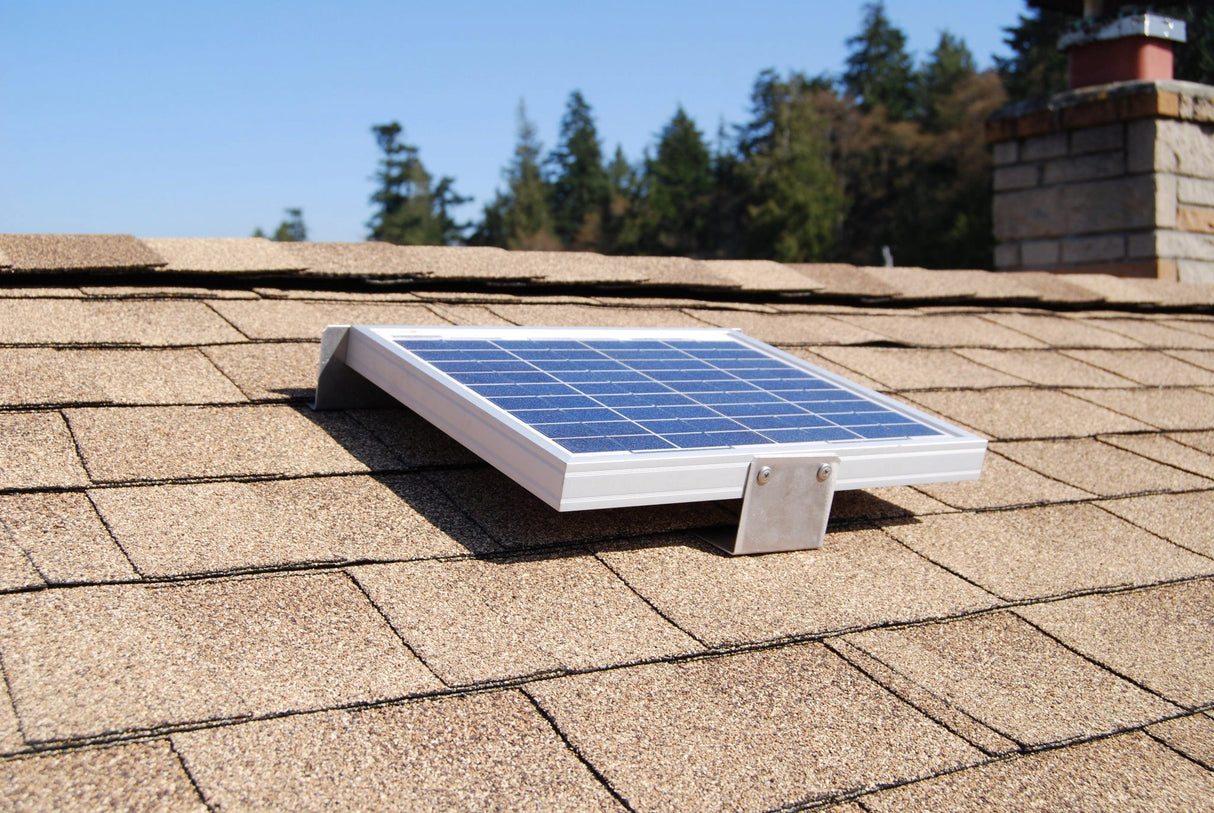 Solar RidgeBlaster has been installed on a brown shingled roof of a house with a chimney in the background.