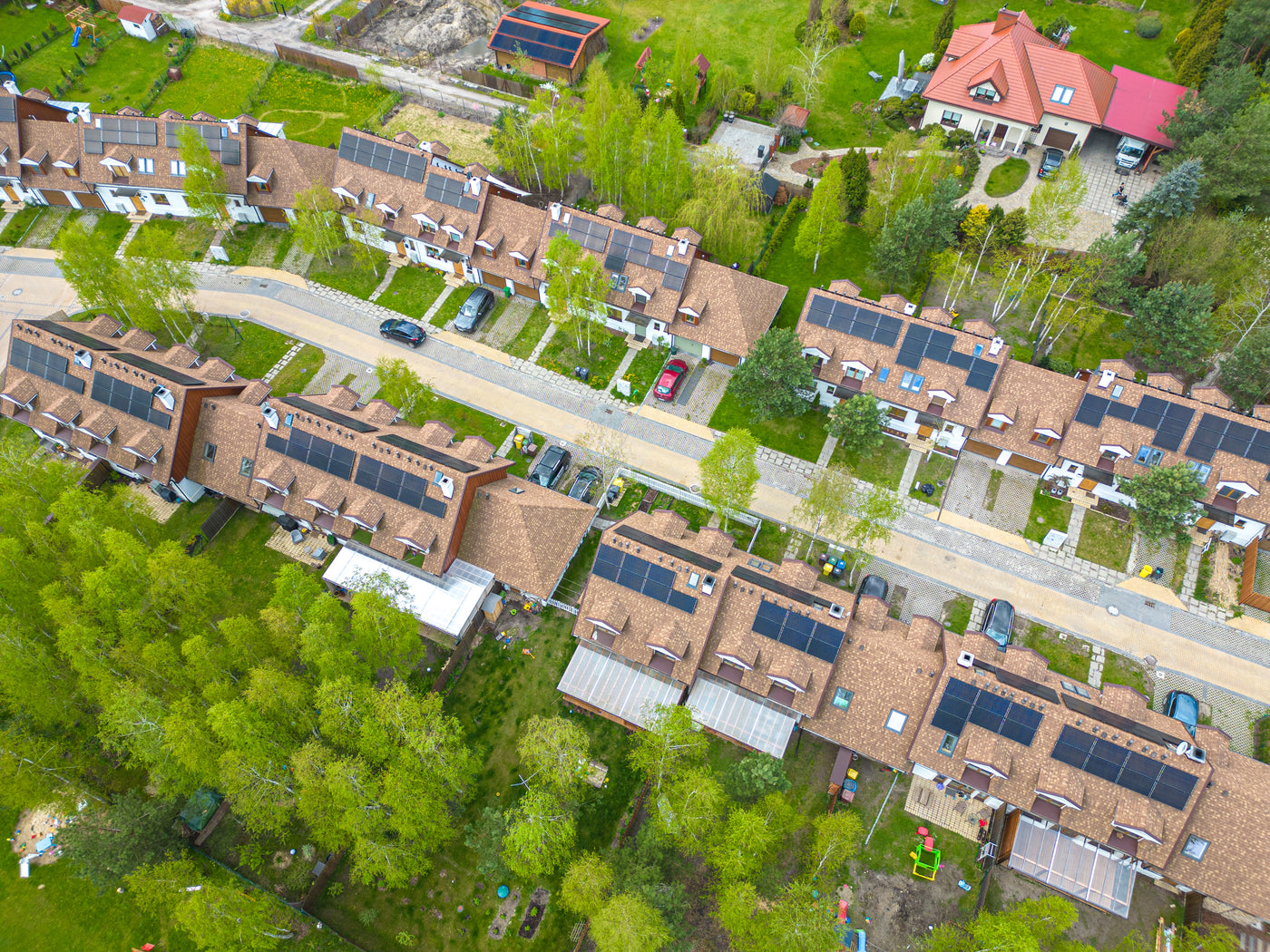 Aerial view of a residential area with houses featuring solar panels on their roofs.