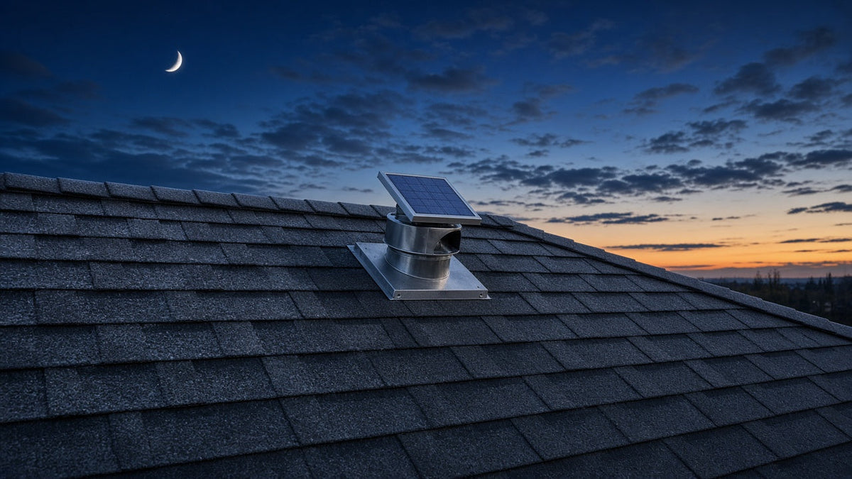 Round solar attic fan with a small solar panel flashed into the shingles near the ridge of a roof at winter dusk under a crescent moon