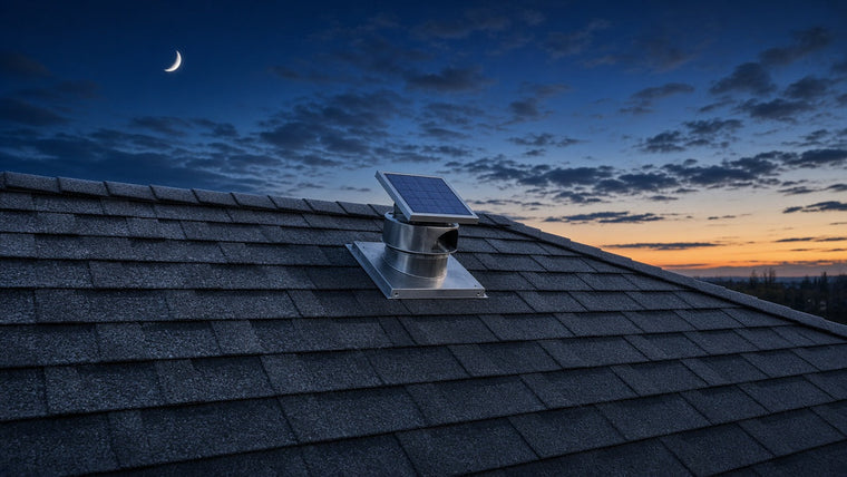 Round solar attic fan with a small solar panel flashed into the shingles near the ridge of a roof at winter dusk under a crescent moon