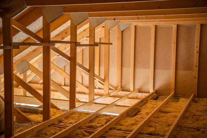 Wooden framing of an attic under construction with insulation.