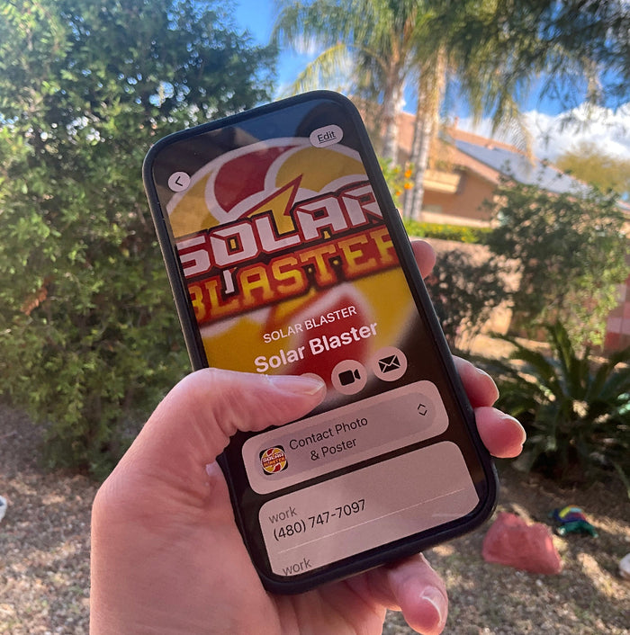 Hand holding an iphone displaying the Solar Blaster Contact and thumb is pushing the Call button. There is a blurred outdoor background.