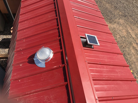 A Solar LightBlaster for Metal Roofs is installed on shed's red metal roof with a Solar Metal RidgeBlaster installed on the other side of the roof.