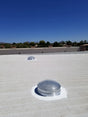 Two 28-inch Solar LightBlaster Tubular Skylights for Warehouses installed on a flat foam roof on top of a warehouse.
