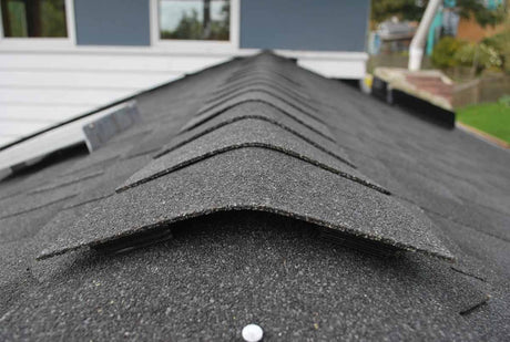 Solar RidgeBlaster has been installed on a dark gray shingled roof and this is a close-up of the shingled ridgecap.