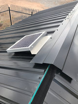 Solar RidgeBlaster has been installed on a dark gray metal roof of a shed with the metal ridge cap being installed as the last step.
