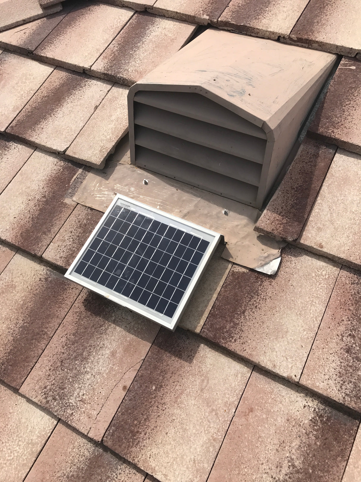 Shows a Solar Tileblaster installed on a dormer vent on a flat-tiled roof.