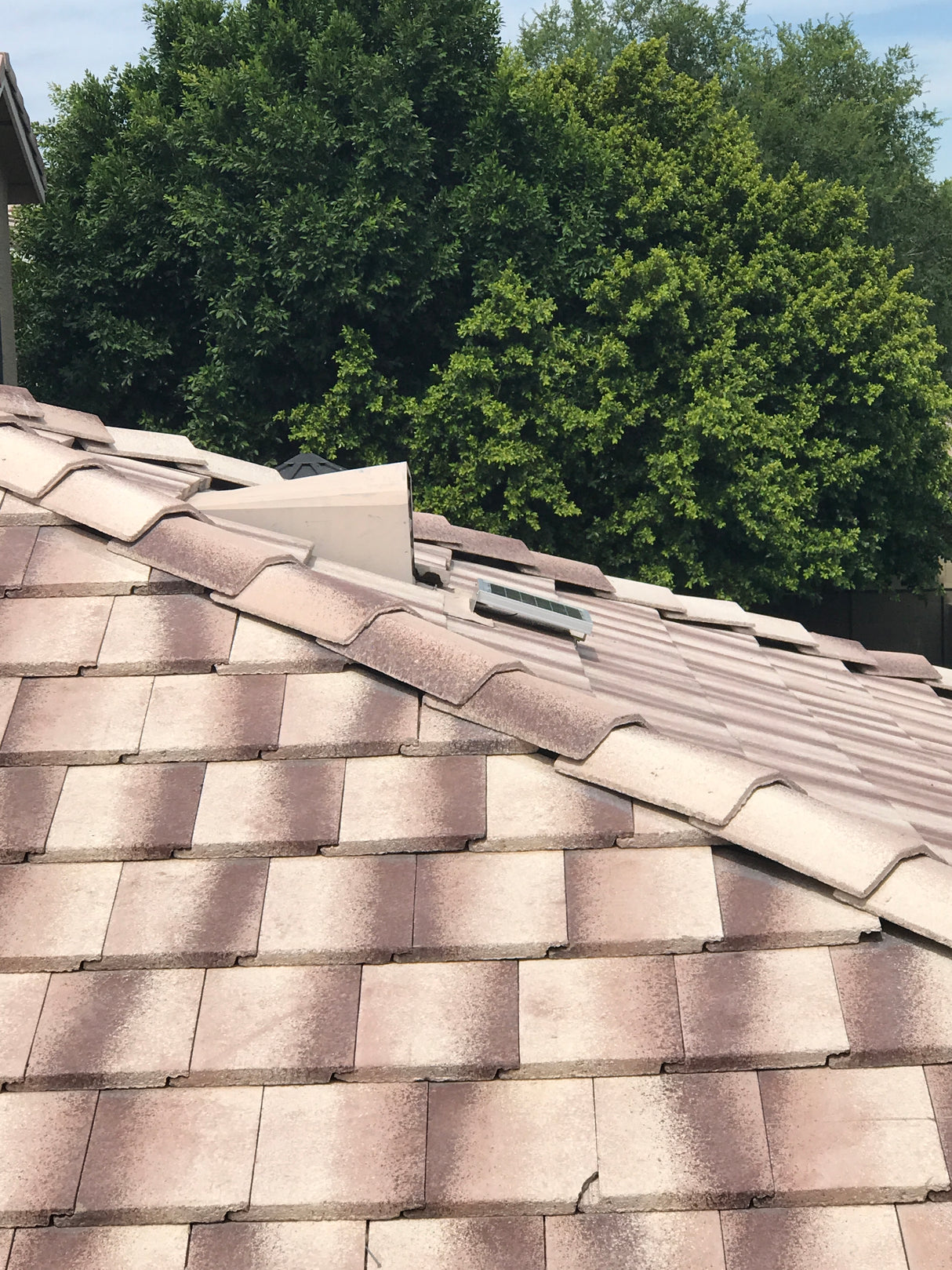 Shows a Solar Tileblaster installed on a dormer vent on a flat-tiled roof.